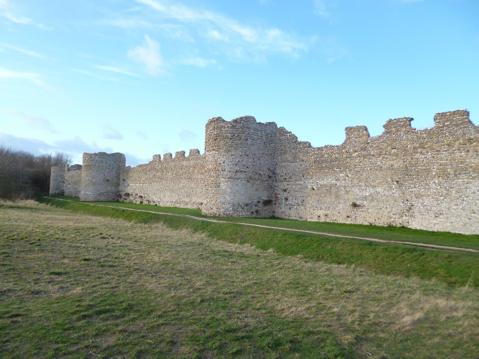 The flint and stone walls and round bastions of Portchester Castle, Fareham, in sunshine